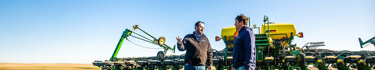 Two Men in a Field Talking in Front of Farming Equipment
